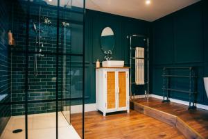 a bathroom with green walls and a sink and a mirror at The Heathcock Boutique Hotel in Cardiff