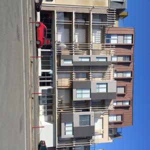 un immeuble avec une voiture rouge garée devant dans l'établissement Résidence Quai Sud-Le Bourdonnais, à Saint-Malo