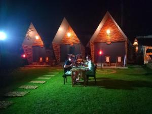twee mensen die 's nachts aan een tafel voor een huis zitten bij Atha Safari Resort & Riverside Camping in Udawalawe