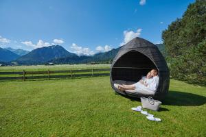 Una pareja acostada en un iglú en la hierba en Schüle's Wellnessresort & SPA Adults Only en Oberstdorf