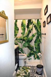 a bathroom with a toilet and a green leafy shower curtain at Apt - Columbia Tusculum - Patio(2) in Cincinnati
