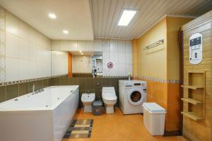 a bathroom with a tub and a toilet and a washing machine at Golden bay in Bar