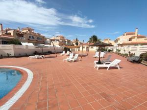 a patio with white chairs and a swimming pool at Casa FLOYD in Caleta De Fuste