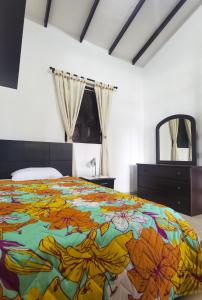 1 dormitorio con 1 cama colorida, tocador y espejo en VILLA ALEJANDRA - Hermosa FINCA cerca al centro - Sendero - Jacuzzi, en Popayán