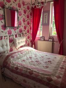 una camera da letto con un grande letto con tende rosse di Maison de gardien , manoir de Pichemont, » la maison des écureuils » 