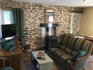 a living room with a couch and a stone wall at Au cottage normand in Saint-James