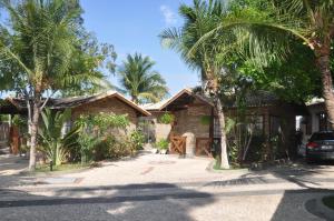 a house with palm trees in front of it at Apart Hotel Chalé Executivo in Mossoró