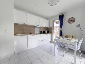 a kitchen with white cabinets and a table and chairs at Nestor&Jeeves - VANINA - Central - Close sea in Nice