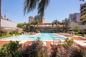 a large swimming pool with chairs and a palm tree at Quartier San Telmo Suites 10 in Buenos Aires