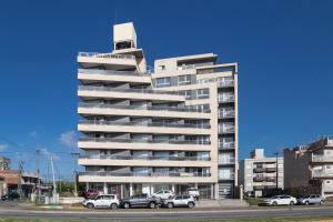 a tall building with cars parked in front of it at Un ambiente frente al mar in Mar del Plata