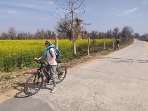 un homme avec un sac à dos et un vélo sur une route dans l'établissement Tourist Pension, à Nawalgarh