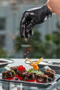 a person wearing black gloves sprinkling food on a plate at Essence Hotel Boutique in Torremolinos