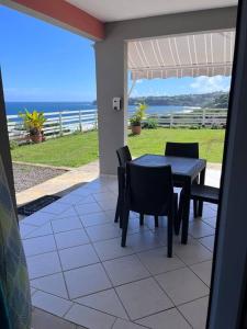 a patio with a table and chairs and the ocean at Les Tourterelles - Appartement vue mer & jacuzzi in Le Lorrain