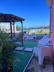 a patio with a bench and a gazebo at Les Tourterelles - Appartement vue mer & jacuzzi in Le Lorrain