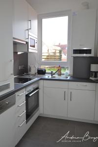 eine Küche mit weißen Schränken und einem Fenster in der Unterkunft Lübbos-Drööm in Borkum