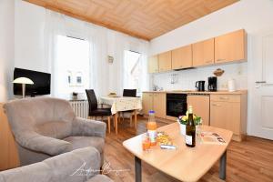 ein Wohnzimmer mit einem Tisch und Stühlen sowie eine Küche in der Unterkunft Haus Herrmann 1 in Borkum