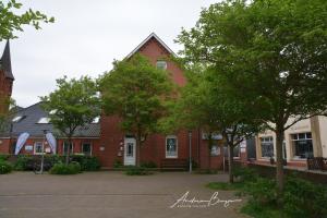 a red brick building with trees in front of it at Haus-Herrmann-1 in Borkum +2 photos