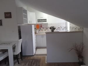 a white kitchen with a table and a white refrigerator at Apartment Iva in Trebinje