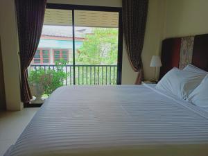 a large white bed in a bedroom with a window at Sri Ngachang in Chiang Mai