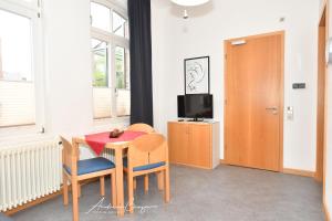 ein Esszimmer mit einem Tisch, Stühlen und einem TV in der Unterkunft Gästehaus St. Josef 2 in Borkum