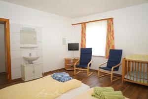 a room with a crib and two chairs and a sink at Haus-Koenigsduene-I-3 in Borkum