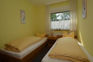 2 Betten in einem kleinen Zimmer mit Fenster in der Unterkunft Haus Bünzow 2 in Borkum
