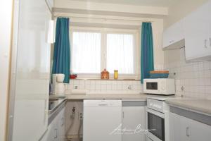 eine Küche mit weißen Geräten und blauen Vorhängen in der Unterkunft Haus Heizmann in Borkum