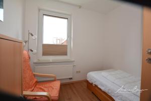 ボルクムにあるGaestehaus-Flandern-4のベッドルーム1室(ベッド1台、窓、椅子付)