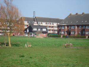 ein Grasfeld mit Gebäuden im Hintergrund mit einem Gebäude in der Unterkunft Olde Baas in Borkum