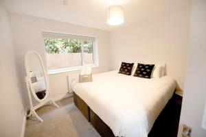 a bedroom with a large white bed with a window at Garden by the Bay Southport in Southport
