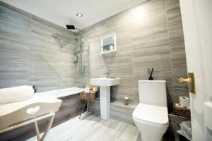 a bathroom with a sink and a toilet and a tub at Garden by the Bay Southport in Southport