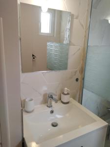 uma casa de banho branca com um lavatório e um espelho em La Maisonnette de Gallerie em Cour-Cheverny