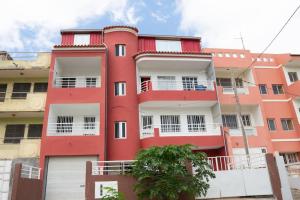 ein rotes Gebäude mit weißen Fenstern und einem Baum in der Unterkunft 3 bedroom apt, near city center, Assomada - LCGR in Assomada