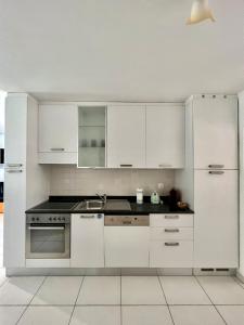 a kitchen with white cabinets and a stove top oven at Appartamento vacanze Sanzen - Como Cernobbio Lugano in Morbio Inferiore