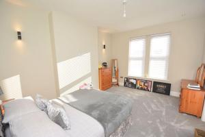 a bedroom with a bed and a dresser and windows at Modern luxury home in Wallasey
