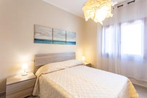 Habitación blanca con cama y lámpara de araña. en Casamorle, en Isola Rossa