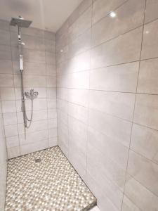 a bathroom with a shower with a tiled floor at Loft proche des plages et sites du débarquement in Osmanville