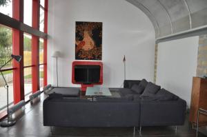 Maison Le Corbusier في Doncourt-lès-Conflans: غرفة معيشة مع أريكة سوداء وتلفزيون
