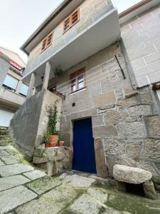 un bâtiment en pierre avec une porte bleue et un banc dans l'établissement A casiña de Luz, à Pontevedra