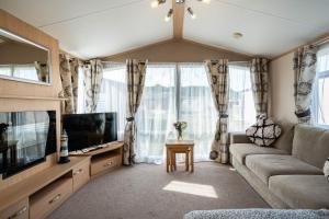 a living room with a couch and a tv at Lyons Retreat in Lossiemouth