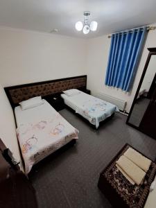 1 dormitorio con 2 camas y espejo en Hotel ISLAM&IMRAN, en Bukhara