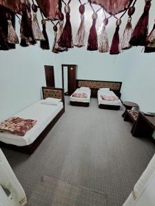 Habitación con 2 camas y mesa. en Hotel ISLAM&IMRAN, en Bukhara