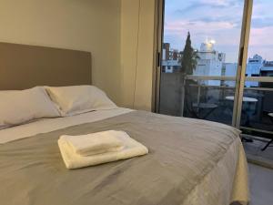 Una toalla blanca sobre una cama con ventana en Departamento en Castelar en Castelar