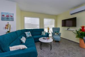 sala de estar con sofá azul y TV en Beach Dream Island House, en Oranjestad