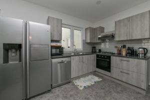 una cocina con electrodomésticos de acero inoxidable y armarios de madera en Beach Dream Island House, en Oranjestad