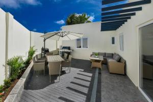 un patio con mesa, sillas y sombrilla en Beach Dream Island House en Oranjestad