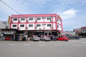 a pink building with cars parked in a parking lot at Q Hotel Temerloh in Temerloh