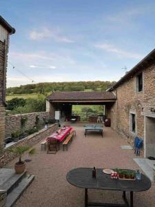 eine Terrasse mit Tischen und Stühlen und ein Gebäude in der Unterkunft Le Pied du Loup - Maison de village clunisois au calme 6-7 personnes in Flagy