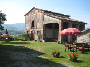 un edificio antiguo con mesa, sillas y sombrilla en Casa riservata sulle colline di Parma oasi di pace en Neviano degli Arduini