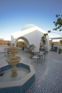 a courtyard with a fountain and tables and chairs at Dar Colibri - Maison d'hôtes à Kélibia in Kelibia
